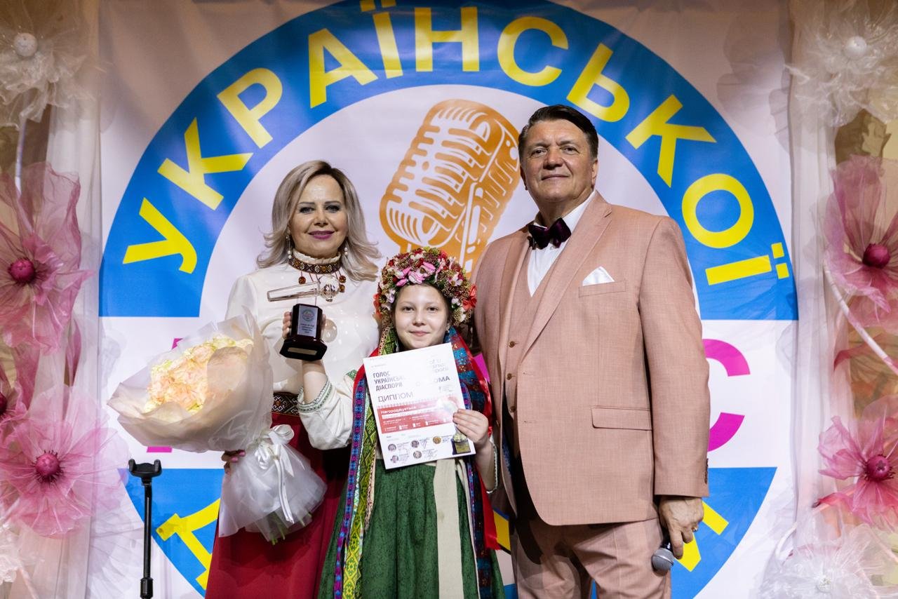 Yaroslav and Nataliya Dub presenting an award to a young performer in traditional dress